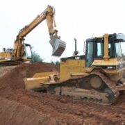 Planierraupe und Bagger bei Erdarbeiten auf einer Baustelle