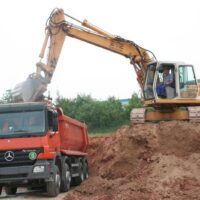 Bagger belädt LKW mit Erdmaterial auf einer Baustelle
