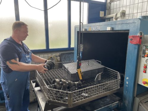 Ein Mitarbeiter räumt Einzelteile in die Teilewaschmaschine.