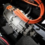 Nahaufnahme eines elektrischen Fahrzeugantriebs mit orangefarbenen Hochvoltkabeln
